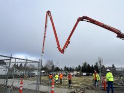 Construction workers pour concrete with large aerial chute for foundation
